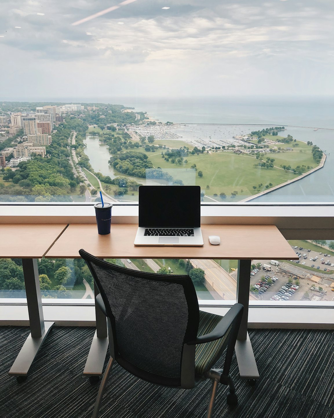 Modern desk with laptop and city view from window.