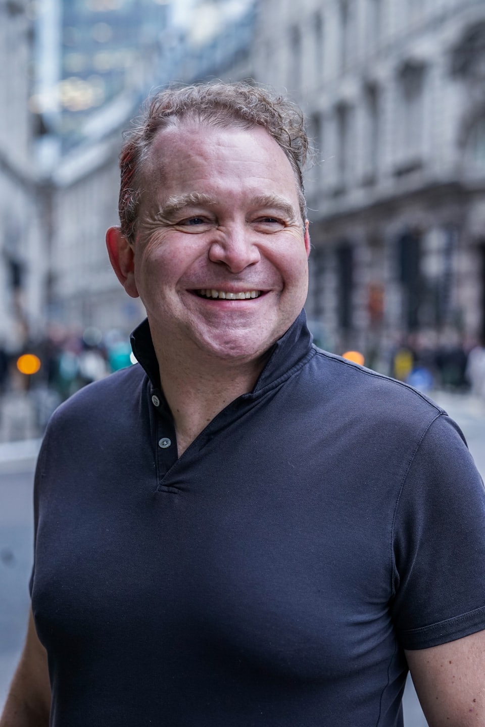 A man in a dark polo shirt standing on a street.